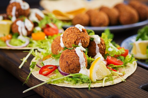 Tortilla envuelta con falafel y ensalada fresca. Tacos veganos. Comida vegetariana saludable.