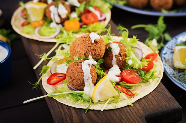 Tortilla envuelta con falafel y ensalada fresca. Tacos veganos. Comida vegetariana saludable.