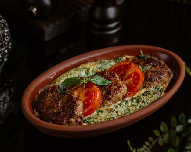 Tortilla de verduras con cotlets, rodajas de tomate y hojas verdes frescas de albahaca