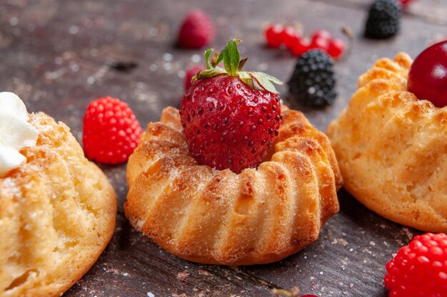 Tortitas con fresas y crema sobre marrón rústico, bizcocho horneado de frutas y bayas