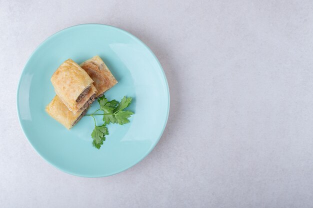 Tortitas en rodajas con carne en un plato, sobre el mármol.