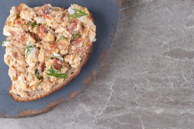 Tostada con huevos revueltos sobre pieza de madera.