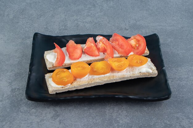 Tostadas crujientes con tomates en placa negra.