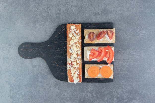 Tostadas crujientes con tomates sobre tabla de madera.