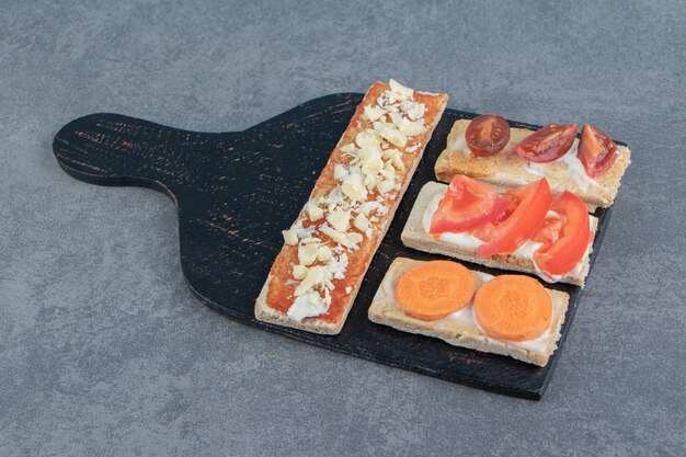 Tostadas crujientes con tomates sobre tabla de madera.