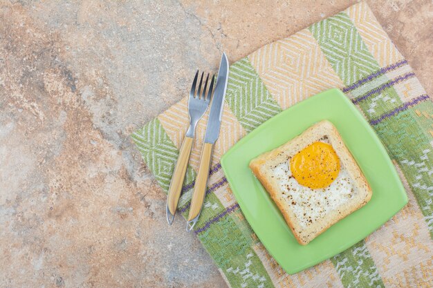 Tostadas de huevo con especias en placa verde con cubiertos y mantel