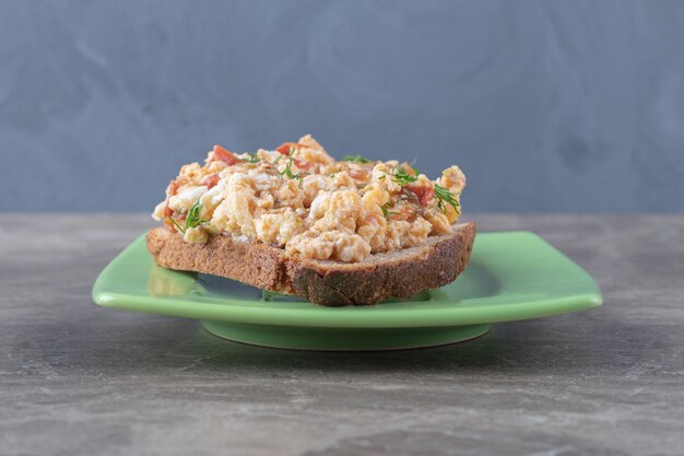 Tostadas con huevos revueltos en placa verde.