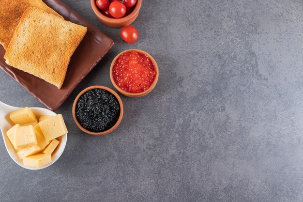 Tostadas con mantequilla y tomates cherry rojos colocados sobre fondo de mármol.