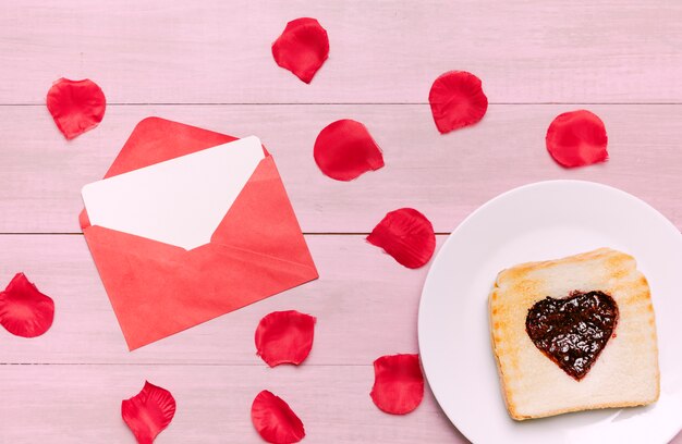 Tostadas con mermelada en forma de corazón con pétalos de rosas.