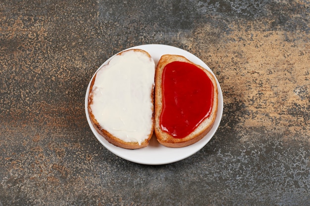 Foto gratuita tostadas con mermelada de fresa y crema agria en un plato blanco.