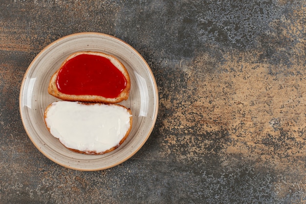 Tostadas con mermelada de fresa y crema agria en plato de cerámica.