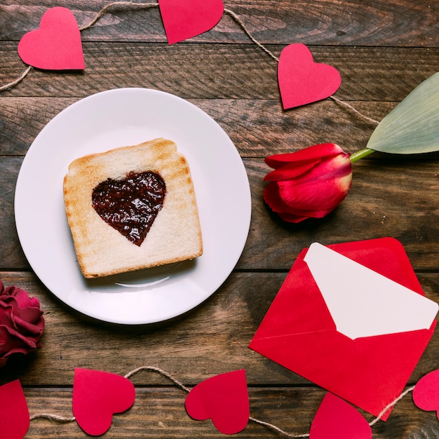 Foto gratuita tostadas con mermelada en un plato cerca de corazones de flores, letras y adornos