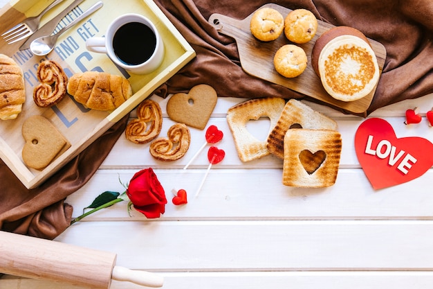 Foto gratuita tostadas y pasteles cerca de rosa y corazón