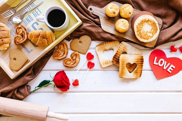 Tostadas y pasteles cerca de rosa y corazón