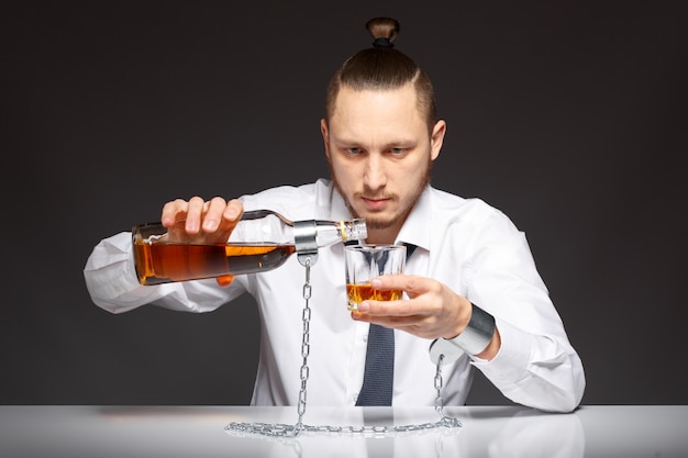Trabajador adicto sirviéndose un whisky