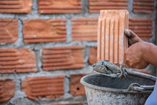 Foto gratuita trabajador de albañilería en la pared exterior con un cuchillo de paleta.