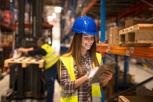 Trabajador de almacén mujer sosteniendo tablet control de inventario en almacén de distribución