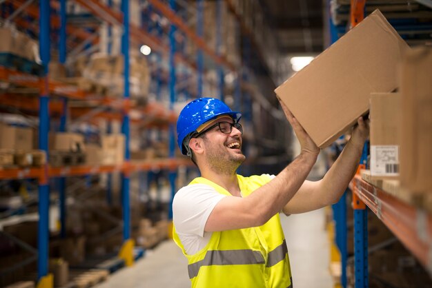 Trabajador de almacén sonriente moviendo cajas en el estante