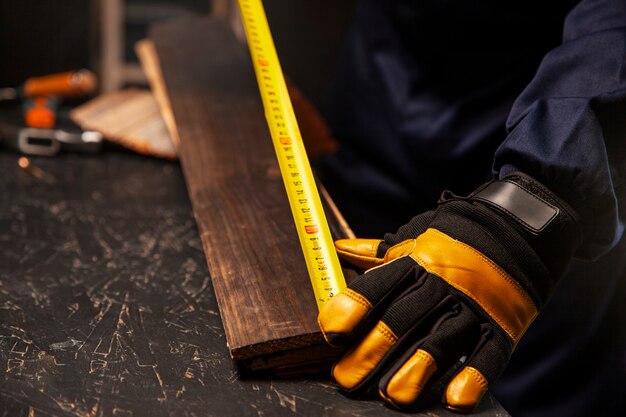 Trabajador de alto ángulo midiendo pieza de madera