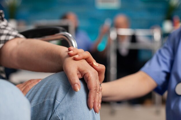 Trabajador asistente social consolando a paciente pensionista discapacitado tocando las manos