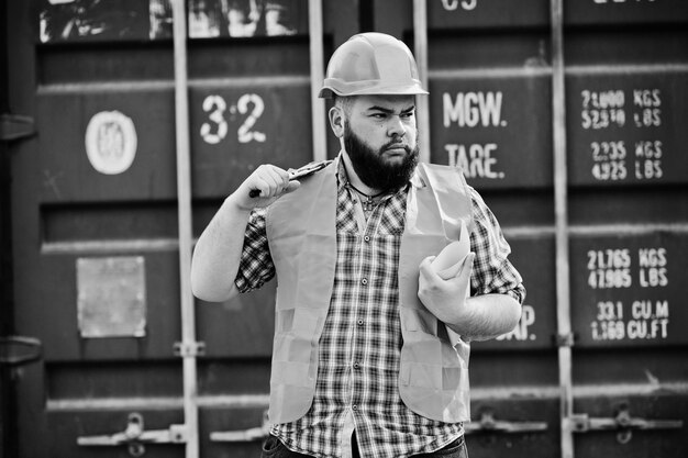 Trabajador de barba brutal hombre traje trabajador de la construcción en casco naranja de seguridad con llave ajustable