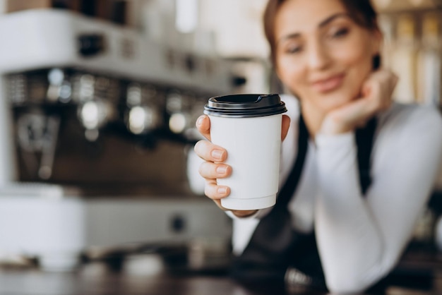 Trabajador barista femenino en una cafetería sosteniendo la taza de café