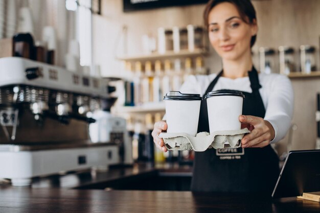 Trabajador barista femenino en una cafetería sosteniendo la taza de café