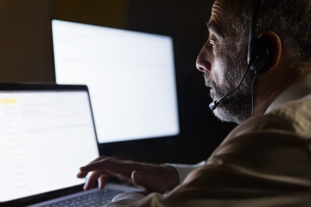 Trabajador de centro de llamadas en auriculares usando laptop