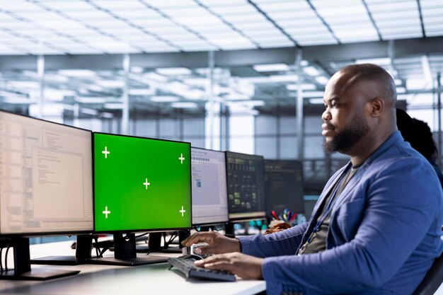 Trabajador en el centro del servidor que utiliza la computadora de pantalla verde para encontrar configuraciones erróneas