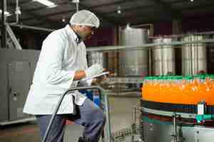 Foto gratuita trabajador comprobando botellas en fábrica de jugos