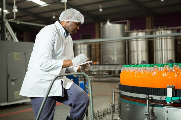 Trabajador comprobando botellas en fábrica de jugos