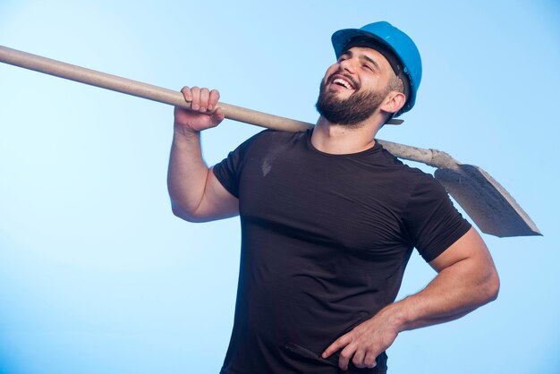 Trabajador de la construcción con casco azul sosteniendo el equipo.