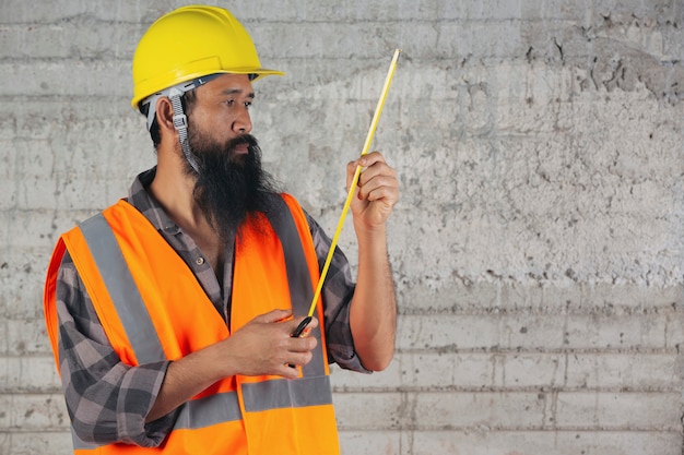 Trabajador de la construcción es una cinta métrica y pensando en el plan en el sitio de construcción.