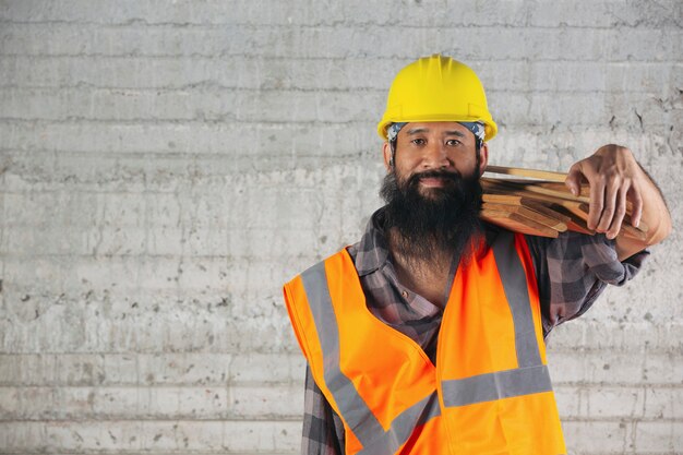 Trabajador de la construcción lleva tablones de madera muy duro en el sitio de construcción.