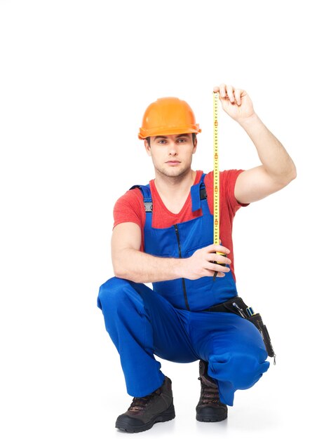 Trabajador de la construcción midiendo la pared en blanco