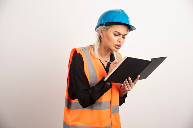 Trabajador de la construcción de mujer escribiendo en el cuaderno. Foto de alta calidad