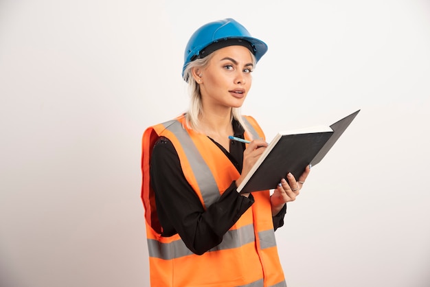 Trabajador de la construcción de mujer escribiendo en el cuaderno. Foto de alta calidad