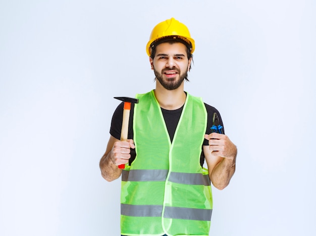 Foto gratuita trabajador de la construcción con pinzas azules y martillo en la mano.