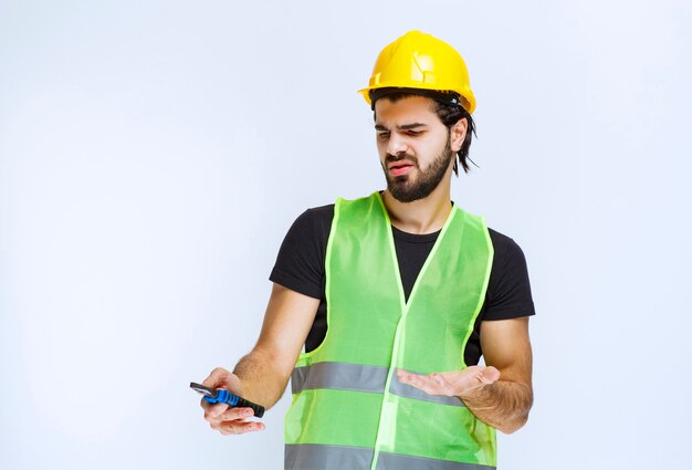 Foto gratuita trabajador de la construcción con pinzas azules y parece confundido e insatisfecho.