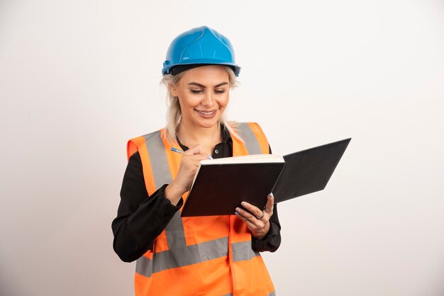 Trabajador de la construcción positivo escribiendo en el cuaderno. Foto de alta calidad