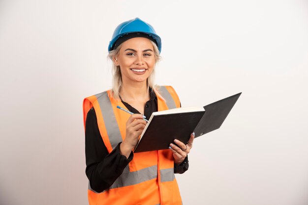 Trabajador de la construcción positivo escribiendo en el cuaderno. Foto de alta calidad