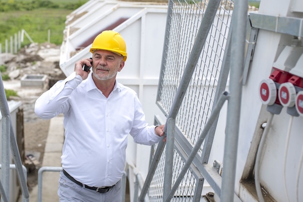 Foto gratuita trabajador de la construcción de sexo masculino con un casco amarillo hablando por teléfono