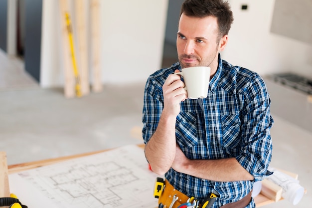 Trabajador de la construcción sincero relajante con una taza de café