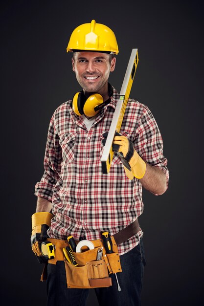 Trabajador de la construcción sonriente sosteniendo la medición