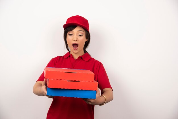 Trabajador de entrega de pizza femenina de pie con tres cartones de pizza.