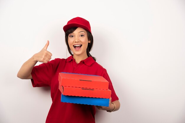 Trabajador de entrega de pizza mujer feliz de pie con tres cartones de pizza.