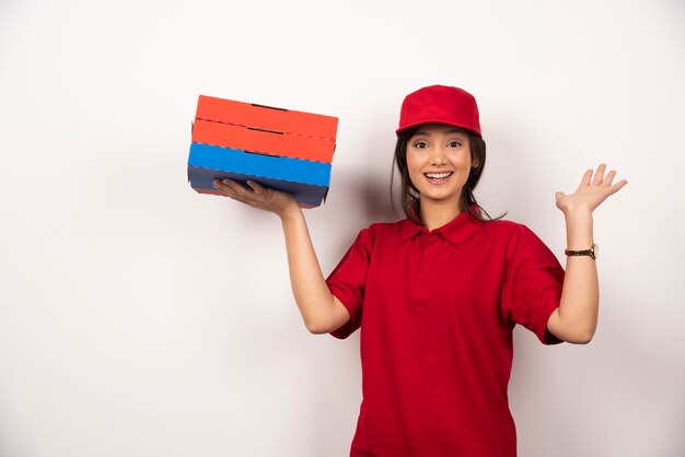 Trabajador de entrega de pizza mujer feliz de pie con tres cartones de pizza.