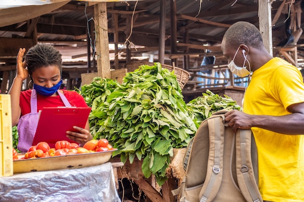 Trabajador de entrega recogiendo un paquete de un comerciante del mercado africano local