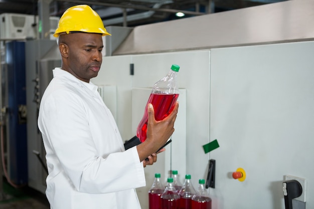 Trabajador examinando botellas en la fábrica de jugos