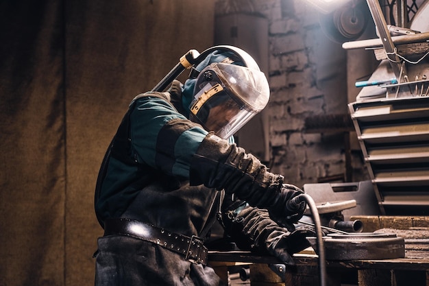 Un trabajador experimentado está reparando piezas metálicas para máquinas herramienta en una fábrica ocupada.